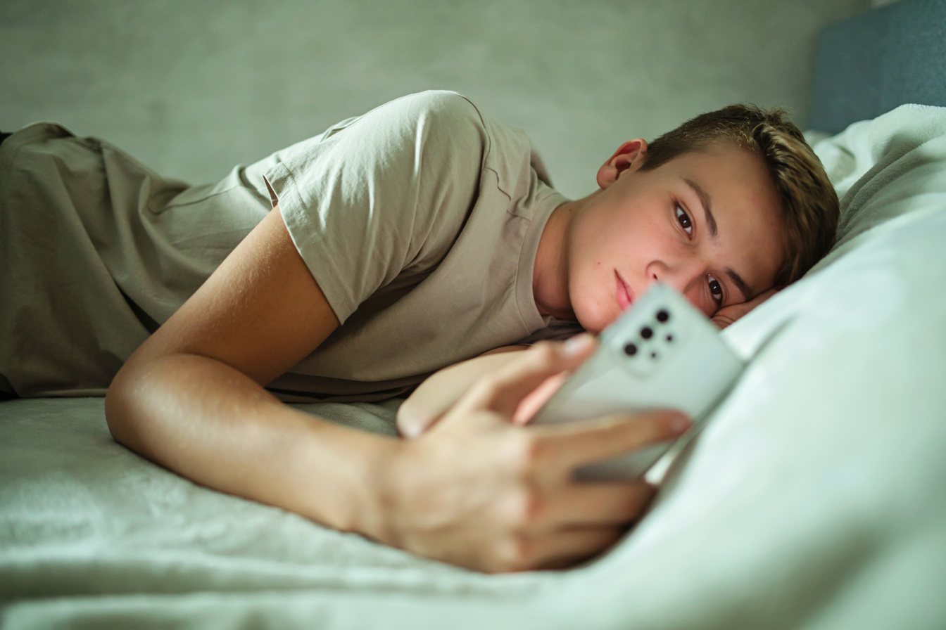 Teenager Using Cell Phone in Bed